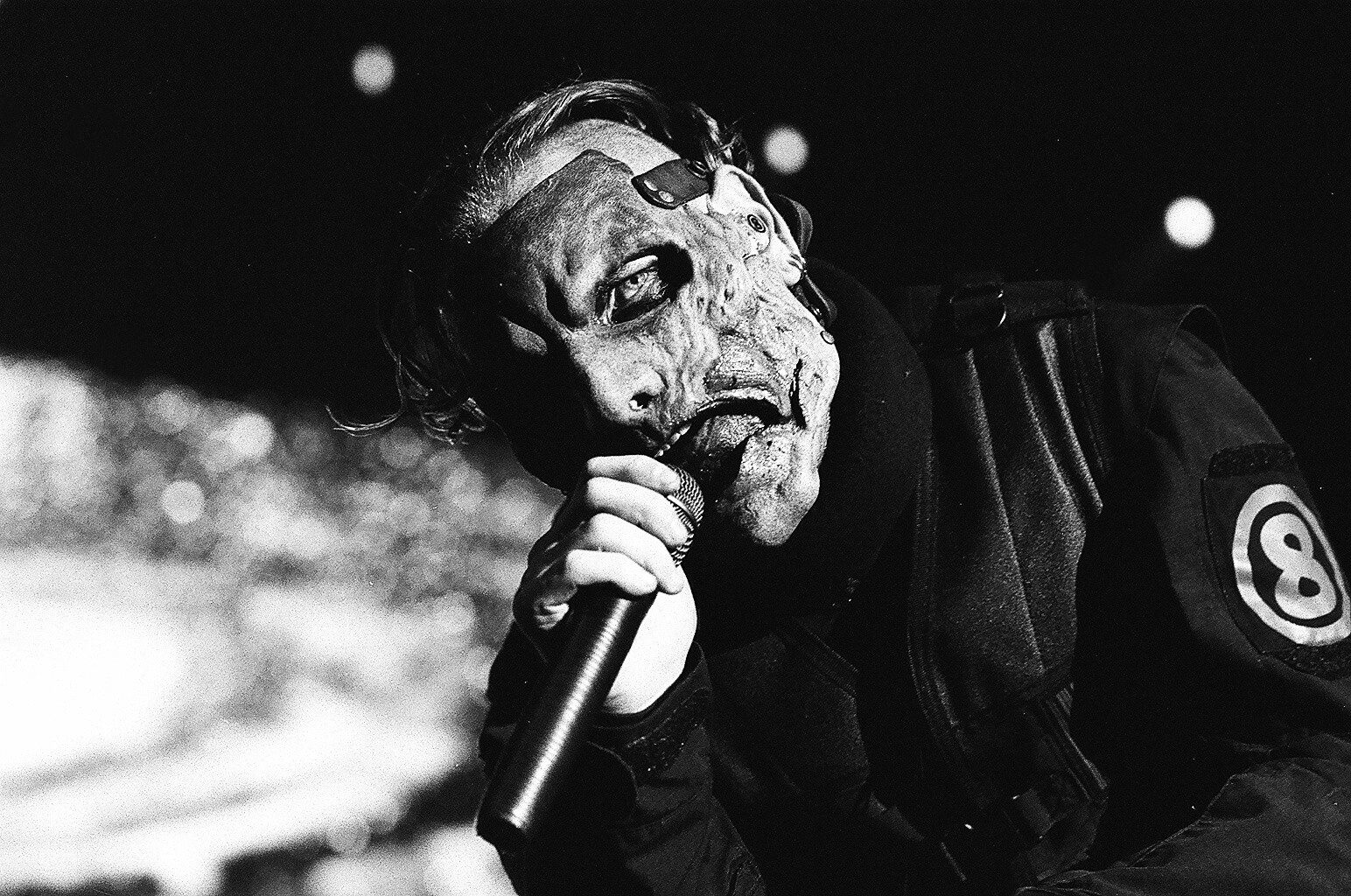 Masked performer singing passionately on stage.