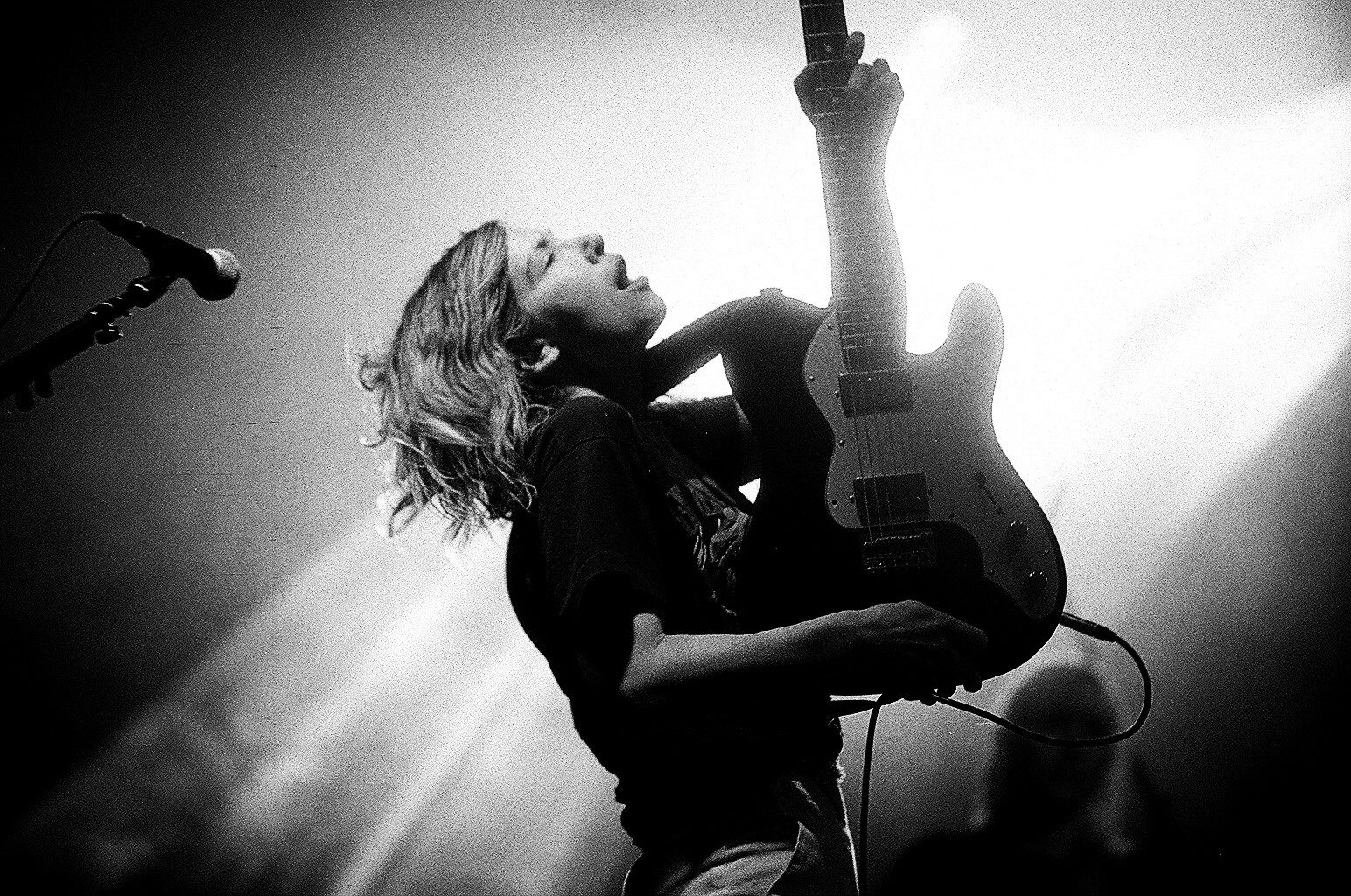 Musician passionately playing electric guitar on stage.