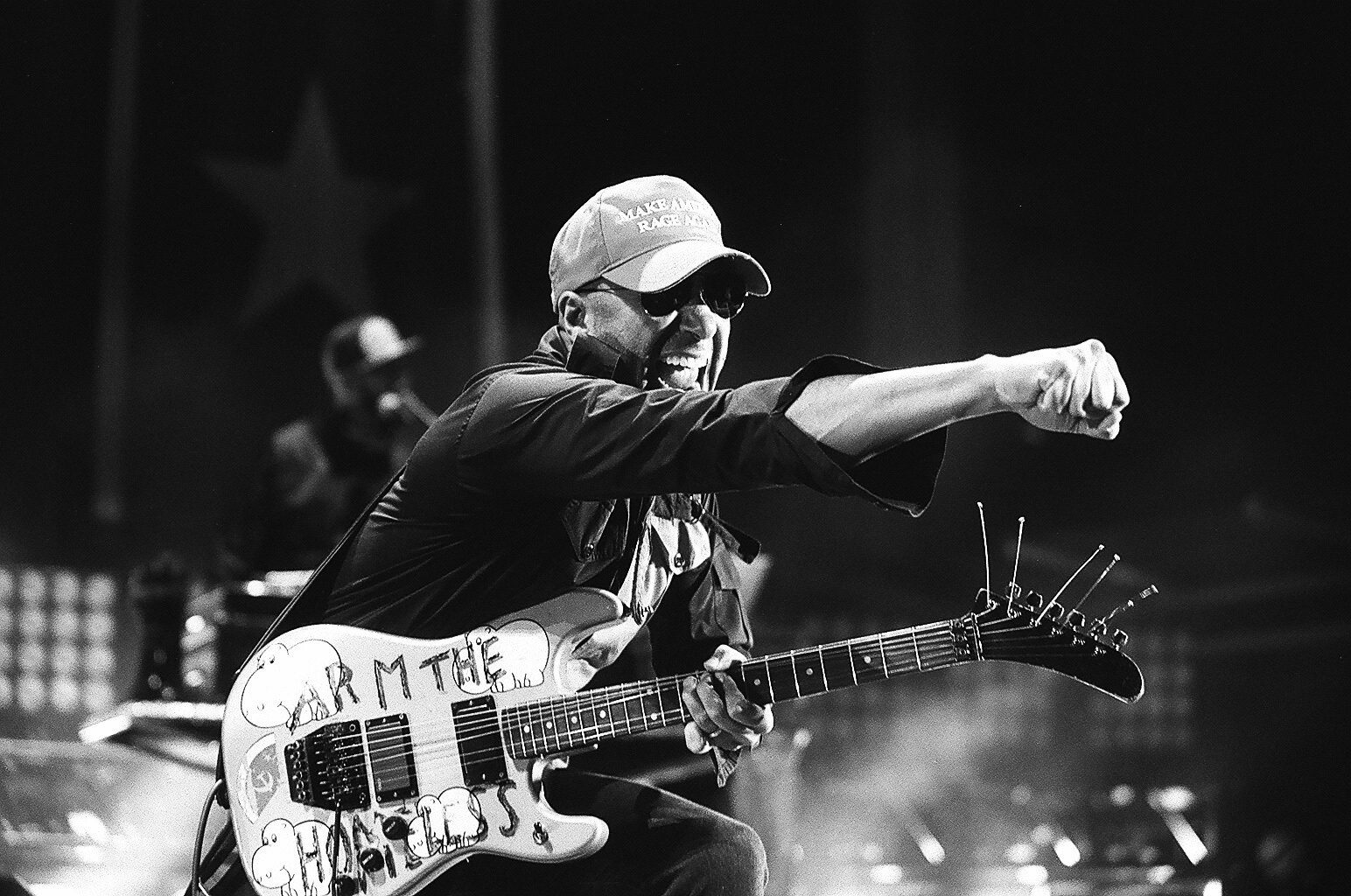 Guitarist performing energetically on stage, monochrome photo.