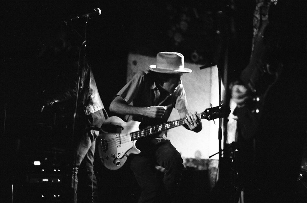 Musician playing guitar on dimly lit stage.