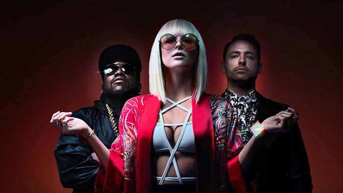 Three stylish people posing against dark background.