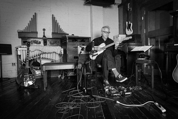 Musician playing guitar in a studio setting.