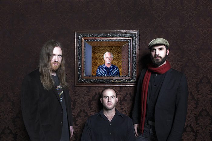 Four men posing, one in a picture frame.