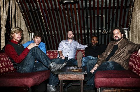 Five men sitting on a red couch.