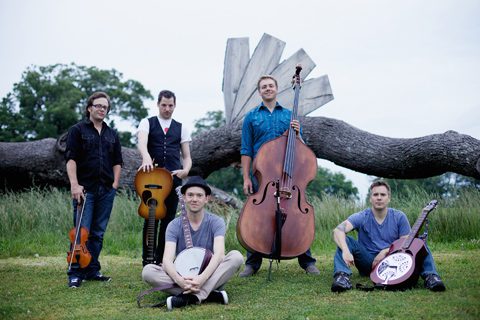 Band posing with instruments in outdoor setting.