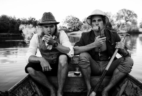 Two men smoking pipes in a boat.