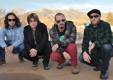 Four men posing outdoors with mountains behind.