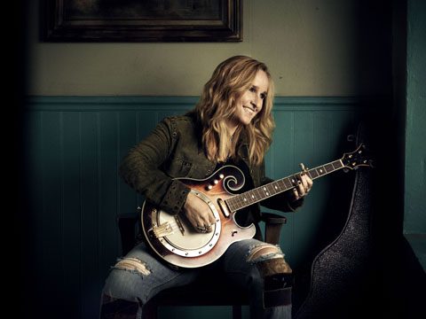 Person playing guitar while smiling indoors.