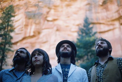 Four people looking up at cliffs.