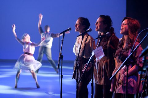 Performers singing and dancing on stage.