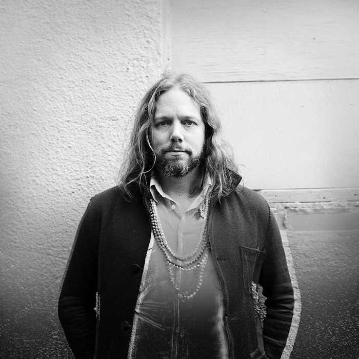 Man with long hair and beard, serious expression.