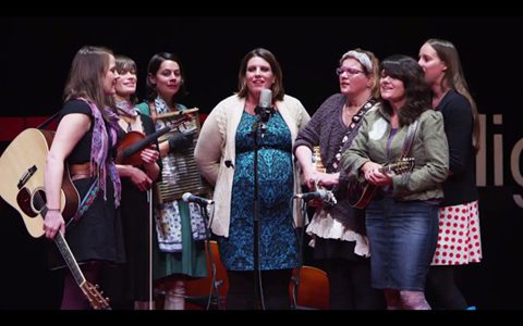 Group of women performing with musical instruments.