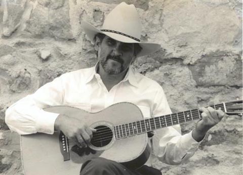 Man in cowboy hat playing acoustic guitar.