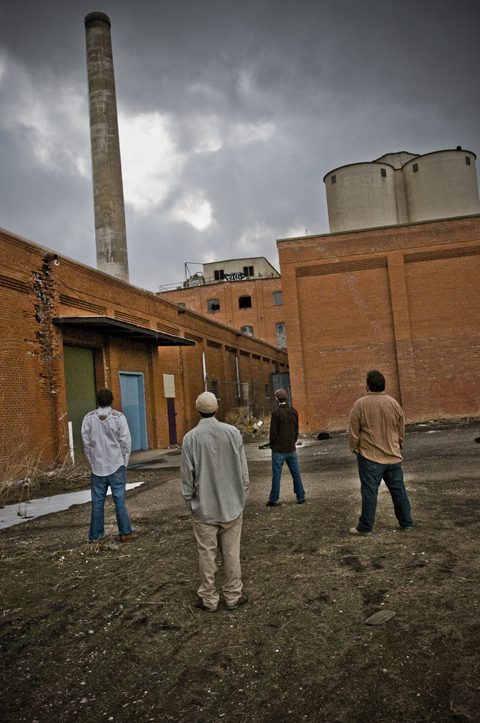 Four people standing near an industrial building.