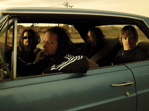Four men sitting in a blue car.
