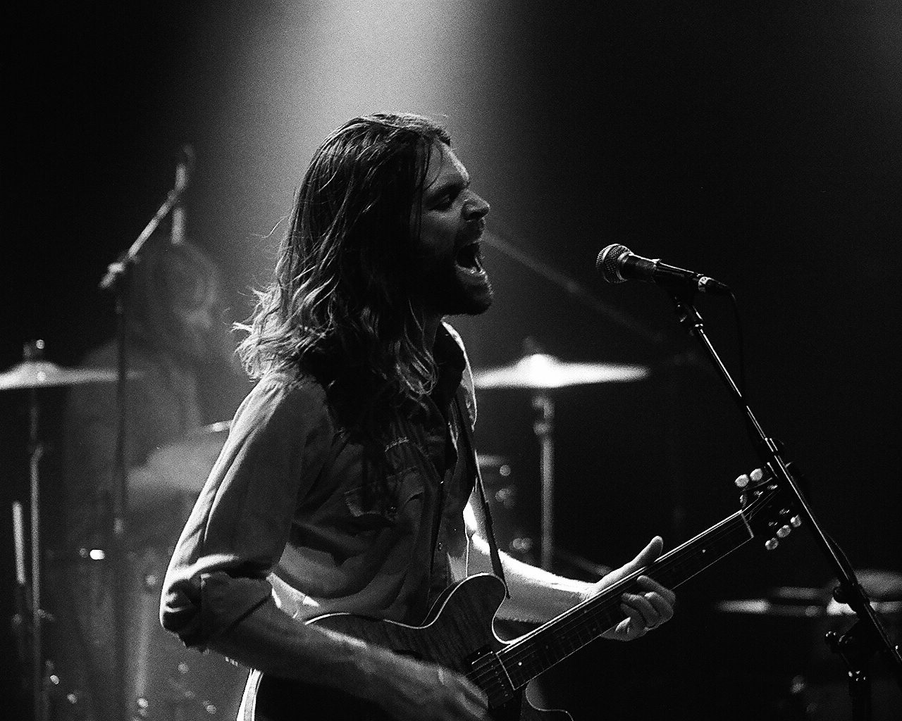 Musician passionately performing on stage with guitar.