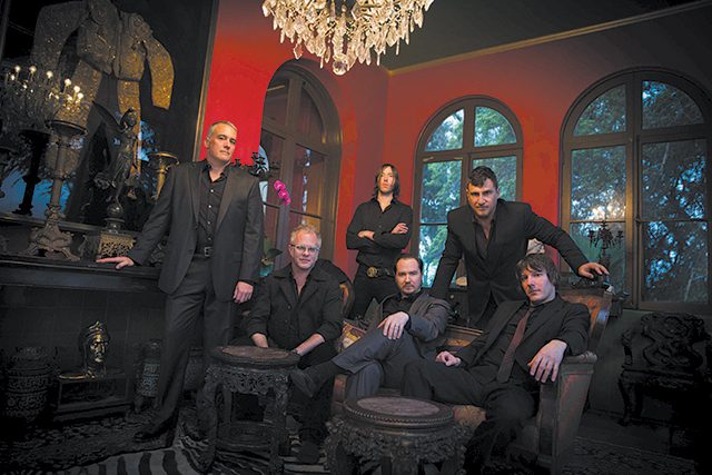 Group of six men in ornate room.
