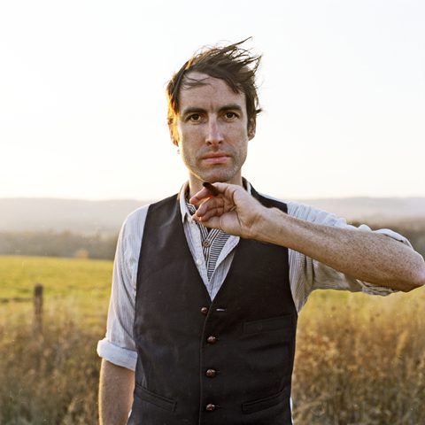 Man standing in field with vest.