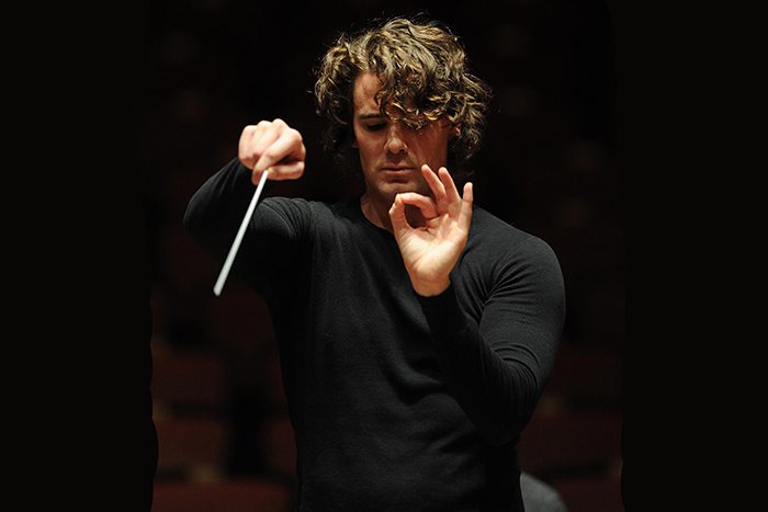 Conductor leading orchestra with baton.