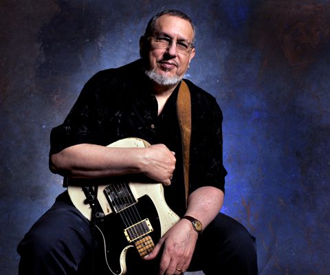 Man holding electric guitar against textured background.