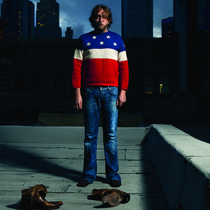 Man in star sweater on rooftop at night.