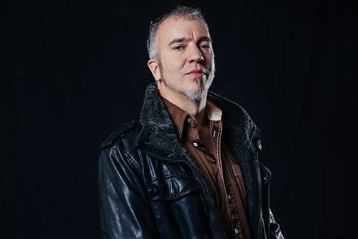 Man in leather jacket, dark background.