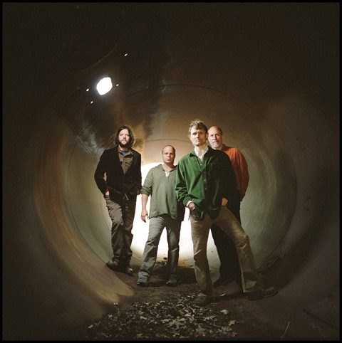 Four men standing inside a large tunnel.