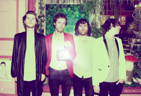 Four men standing in vintage-themed room.