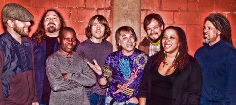 Group of people smiling against brick wall.