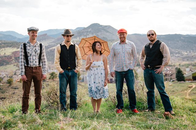 Group posing outdoors with mountains in background.