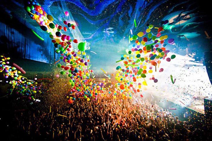 Concert crowd with colorful balloons and confetti.