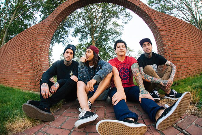 Four people sitting under brick archway.