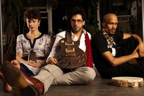 Three people sitting with guitar and tambourine.