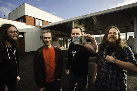 Four people smiling outside a building.