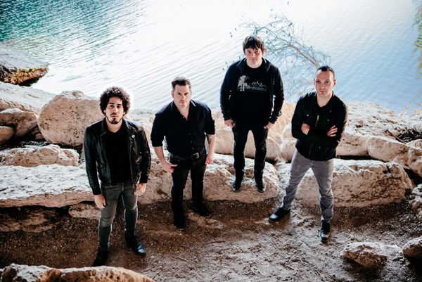 Four men standing on rocky terrain.