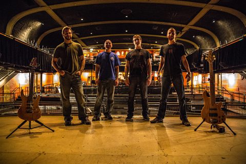 Band posing on stage with instruments.