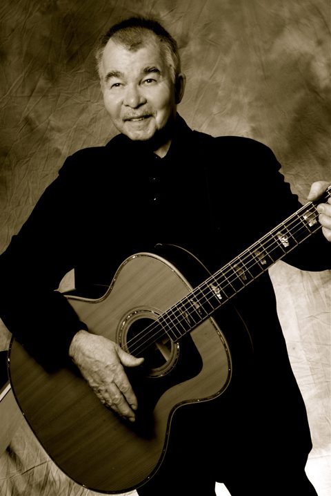 Man playing acoustic guitar, sepia-toned portrait.