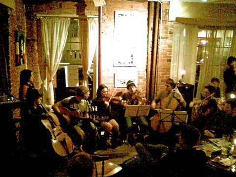 Musicians performing in a cozy, dimly-lit room.