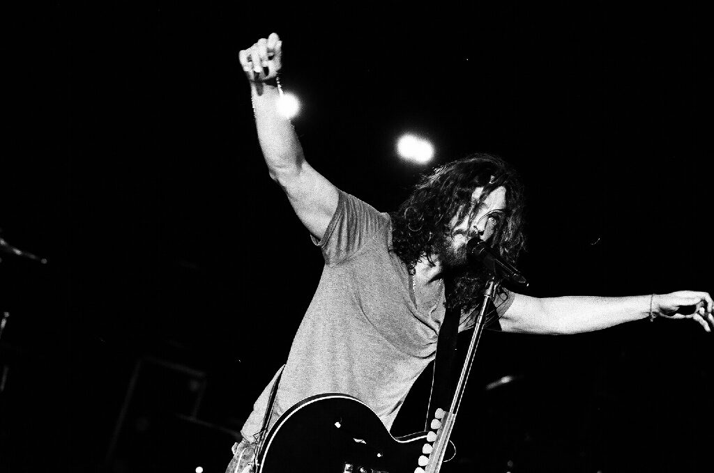 Musician performing energetically with guitar on stage.