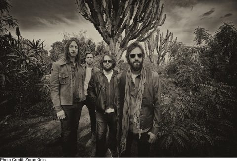 Four men standing in a desert landscape.