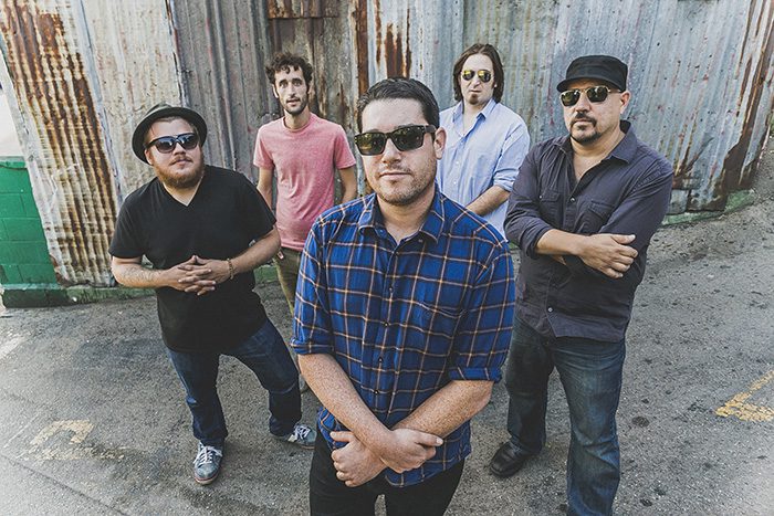 Five men posing in casual outdoor setting.