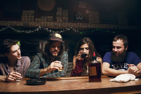 Four people sitting at a bar counter.