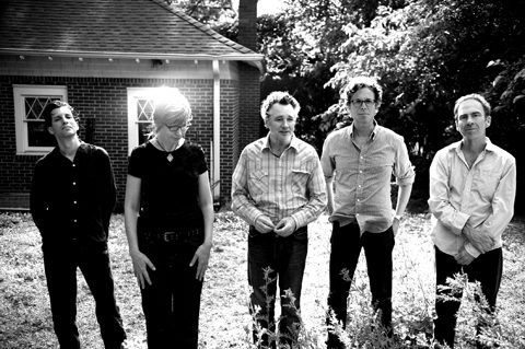 Five people standing outside near a building.