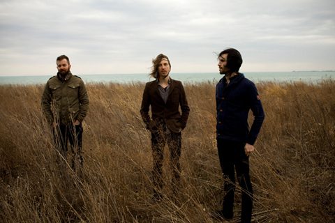 Three people standing in a grassy field.
