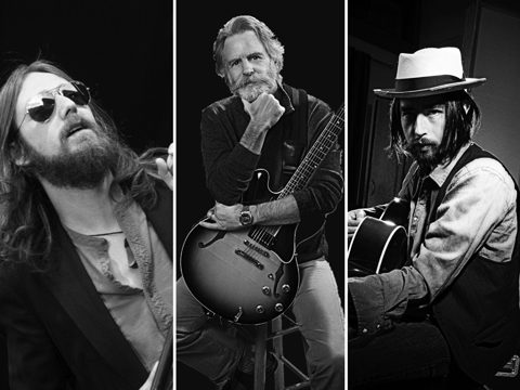 Three musicians with guitars in black and white.