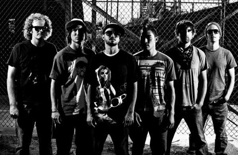 Band members posing in front of fence.