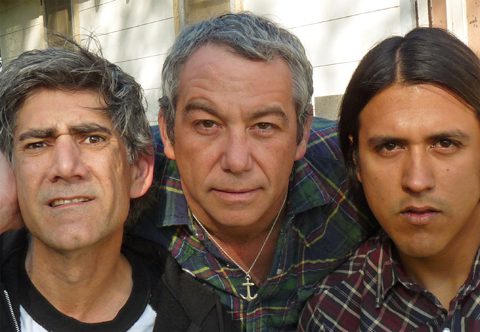 Three men standing closely, looking serious.