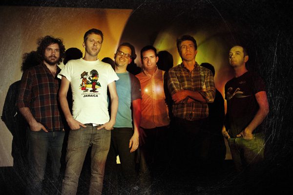 Group of six men posing together indoors.