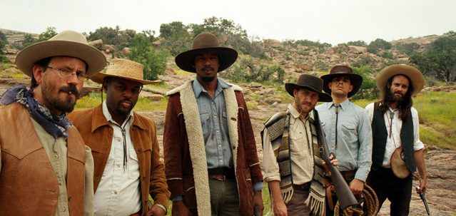Group of cowboys standing in outdoor setting.