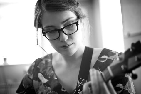 Person playing guitar, wearing glasses, black-and-white.